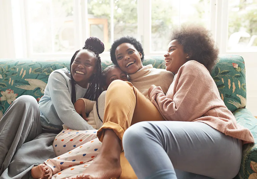 Mother and three daughters laughing on the couch